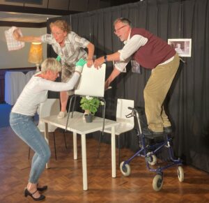 Theater A la Carte voorstelling positieve gezondheid voor markenheem. Twee oude mensen worden van tafel gehaald door verzorgende