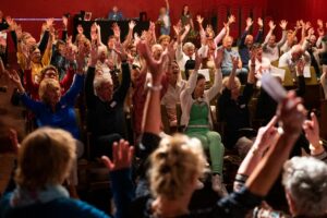 De zaal zingt een lied in de voorstelling over positieve gezondheid van Theater A la Carte voor Viore